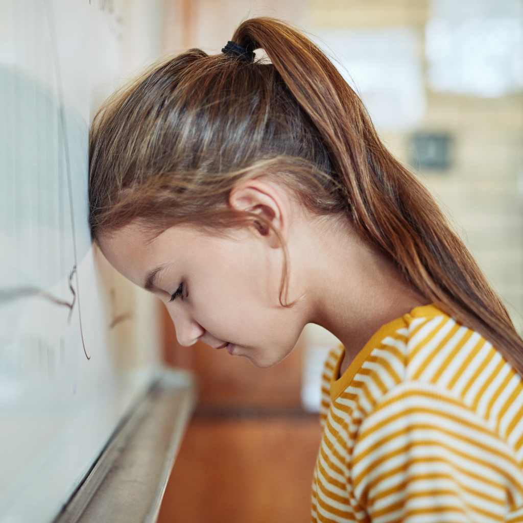 Child leaning head on a wall, illustrating signs of autistic burnout and emotional exhaustion.