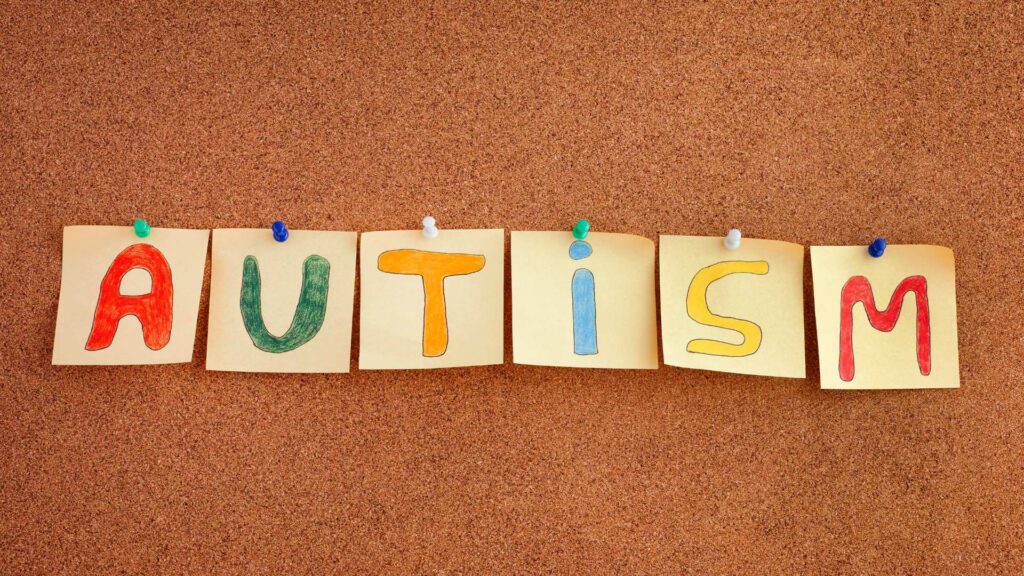 Colorful letters spelling the word autism pinned to a cork board