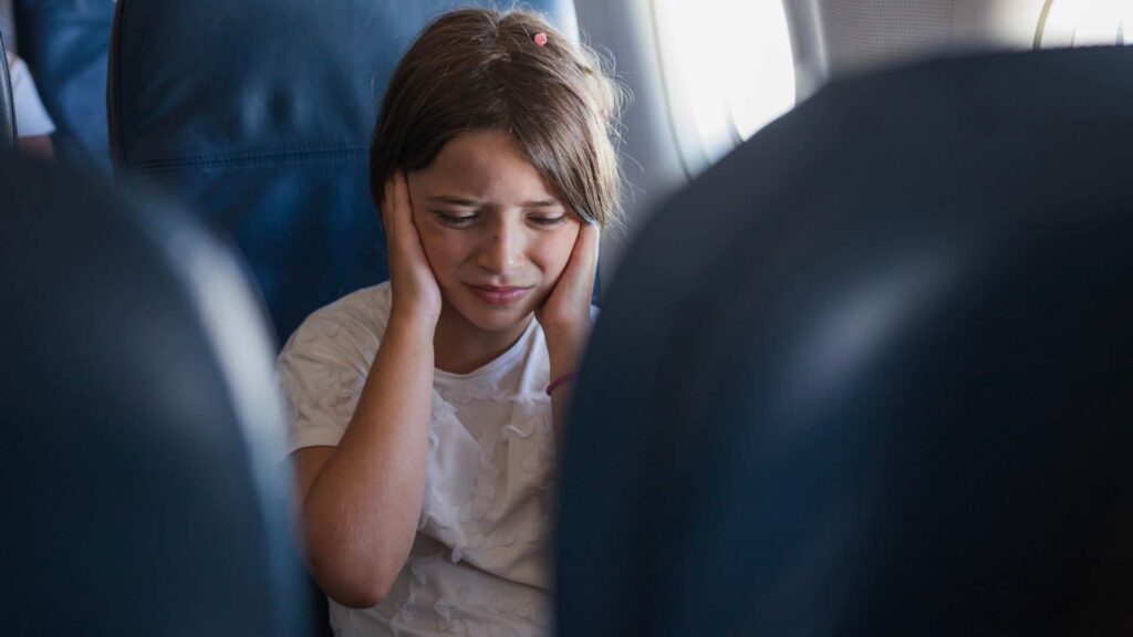 Kids with backpacks looking out at airplanes through large airport windows