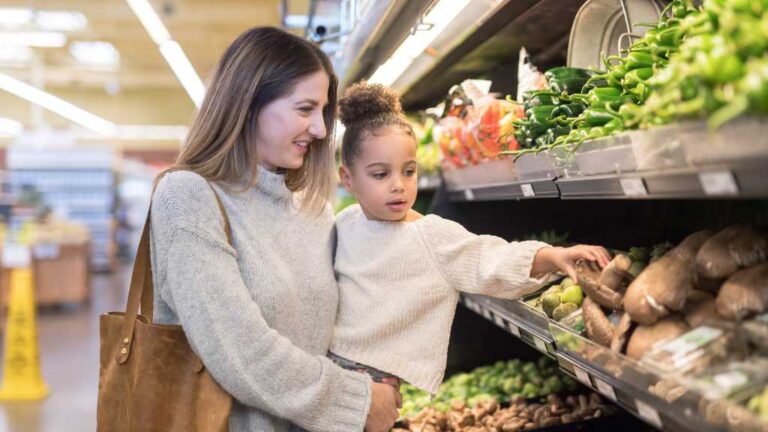 Mother and child shopping for vegetables at a grocery store — autism and outings support guide