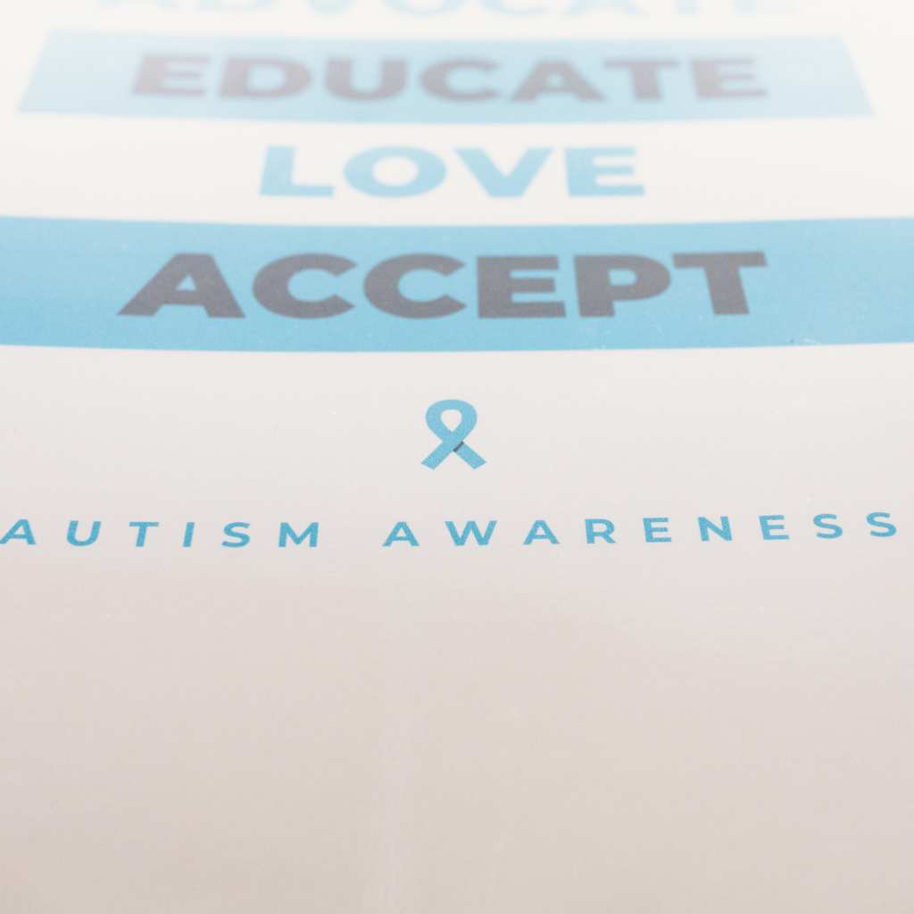 Poster with soft blue text reading Educate, Love, Accept, above a small ribbon and the words Autism Awareness
