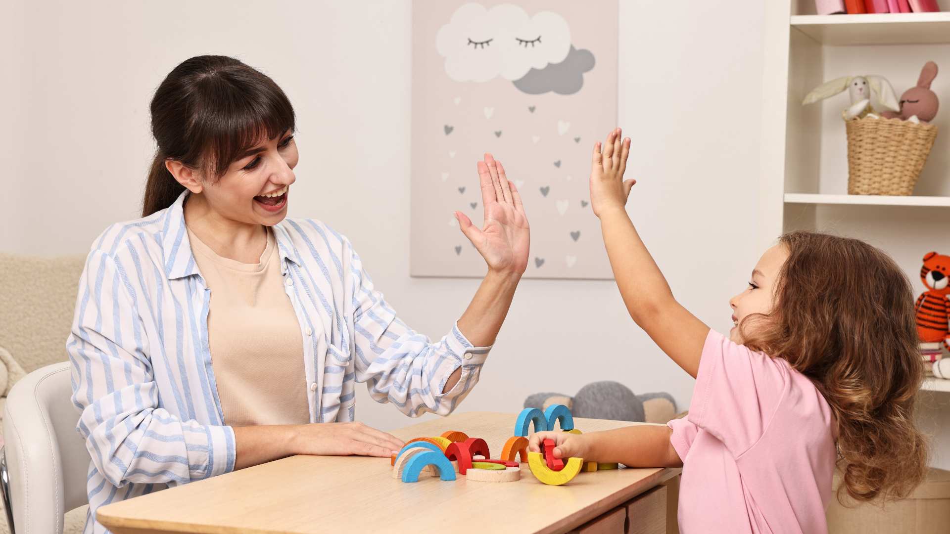 Therapist and child smiling and giving a high‑five during an ABA autism therapy session.