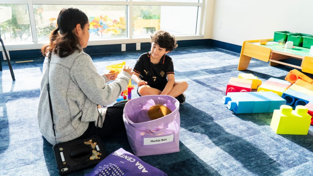 Young child attending an ABA therapy session, engaging in a play-based learning activity with a therapist