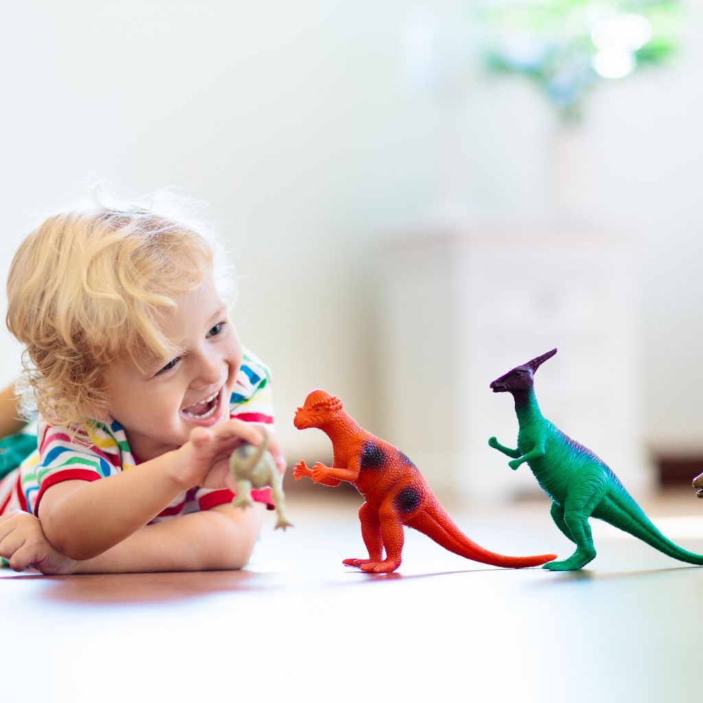 Young child showing intense focus and interest while playing with dinosaur toys, illustrating highly focused interests as a possible autism symptoms.