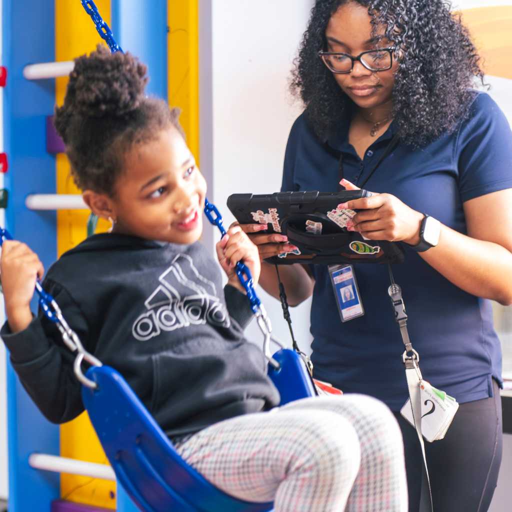 ABA therapist observes a child on a swing during therapy
