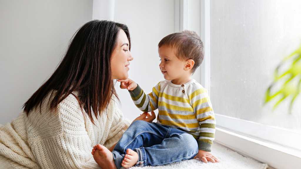 Toddler communicating with caregiver during ABA therapy for speech delay