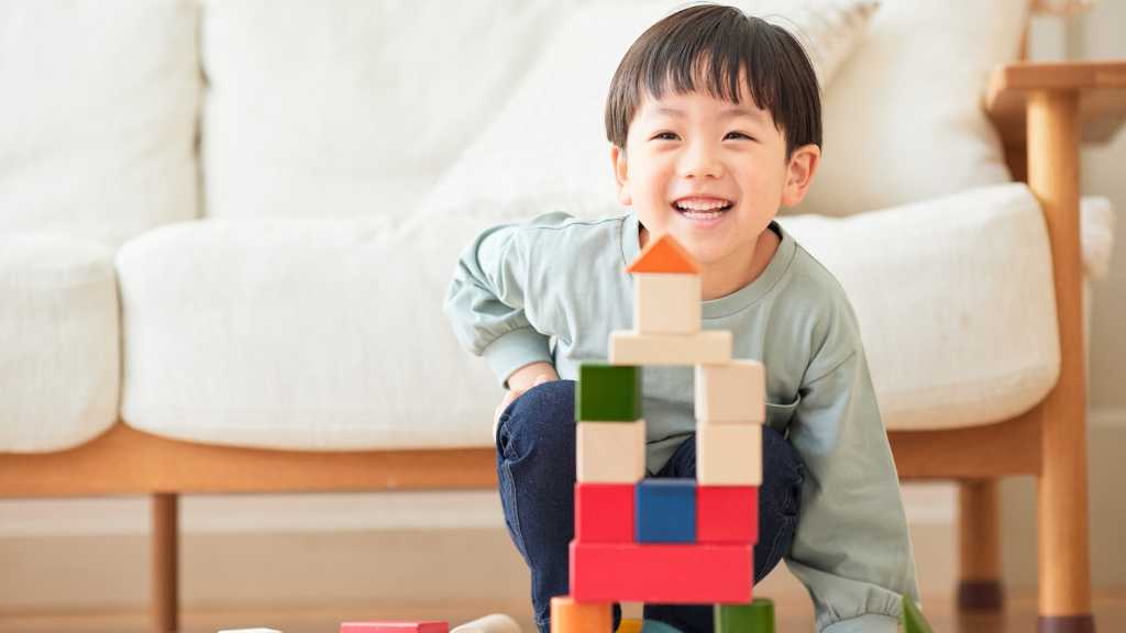 Smiling toddler building blocks during ABA therapy for communication