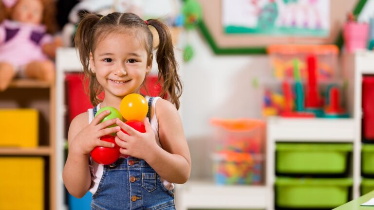 Preschool child playing with colorful balls in a classroom