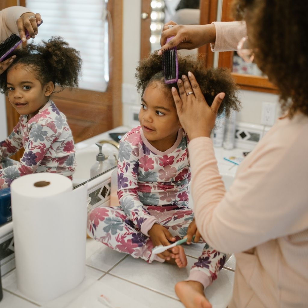 Parent helping a young child with a daily self-care routine