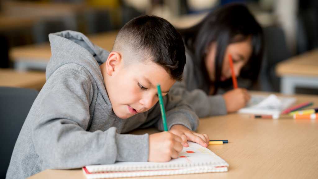Child completing writing activity with autism school support