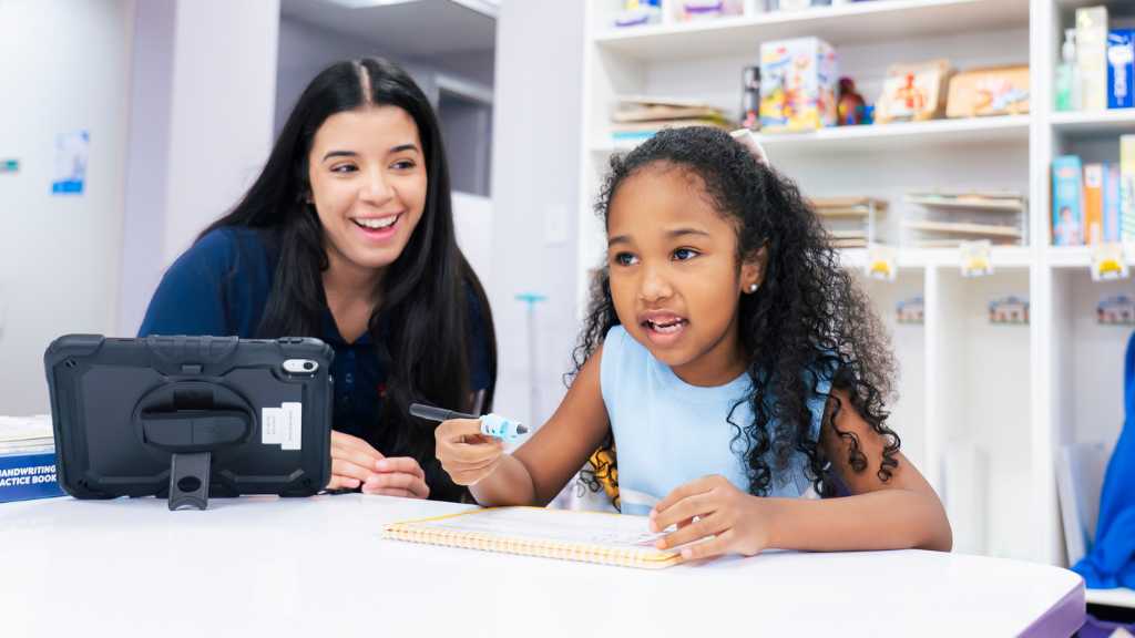 BCBA supervising ABA therapy session with child using tablet