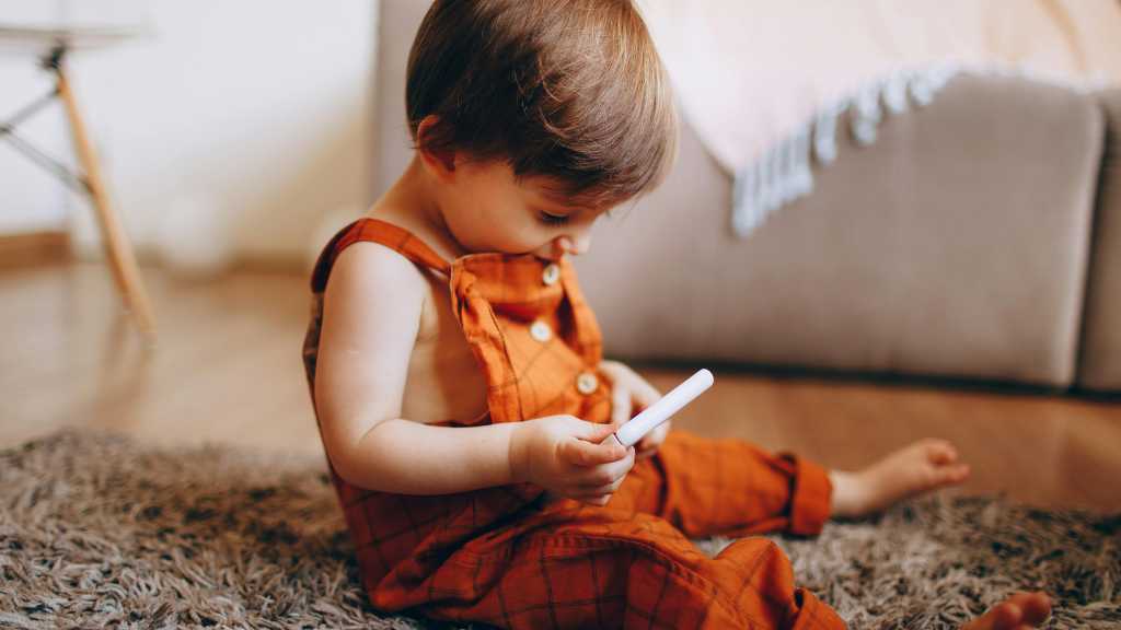 Toddler quietly playing alone holding object late talker signs