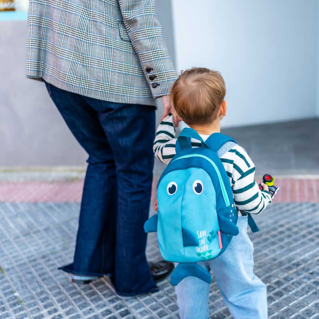 Child with backpack holding caregiver’s hand after autism diagnosis