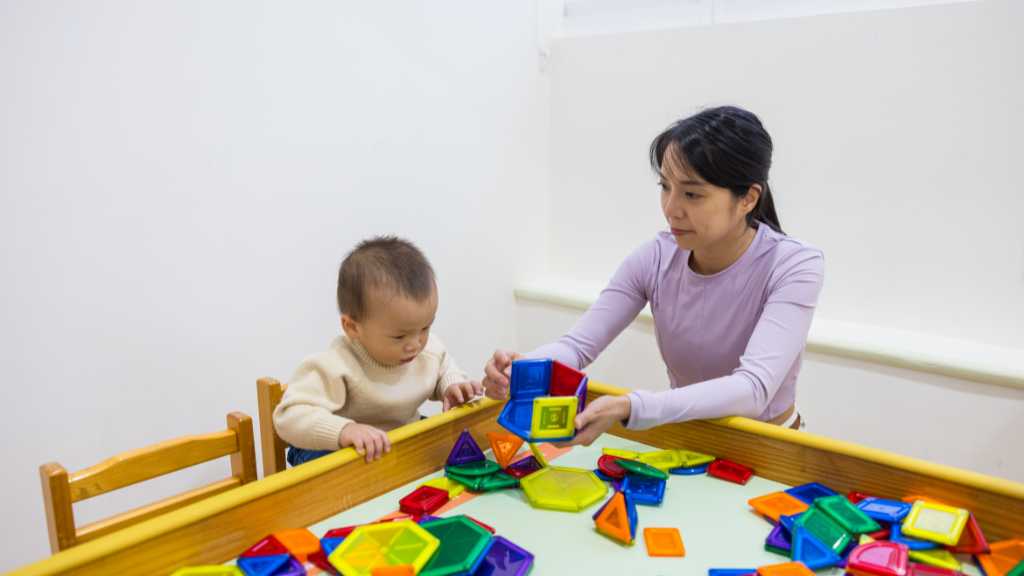 Toddler working with a therapist during early intervention ABA using colorful learning toys