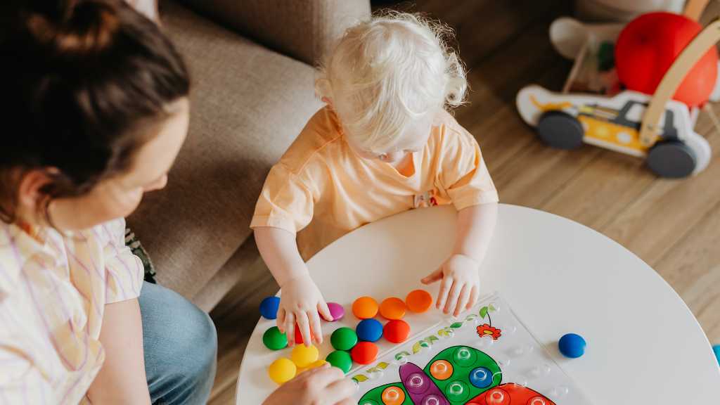 Toddler participating in early intervention ABA therapy with a therapist using colorful learning toys