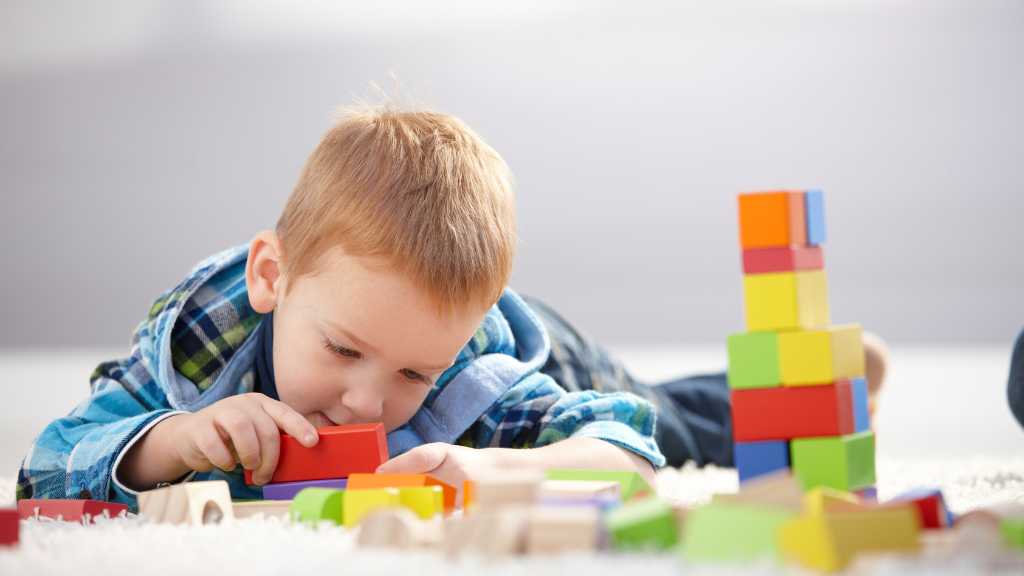 2-year-old focused on stacking blocks, repetitive play and early signs of autism in toddlers