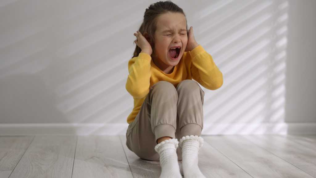 Child covering ears during sensory overload related to autism