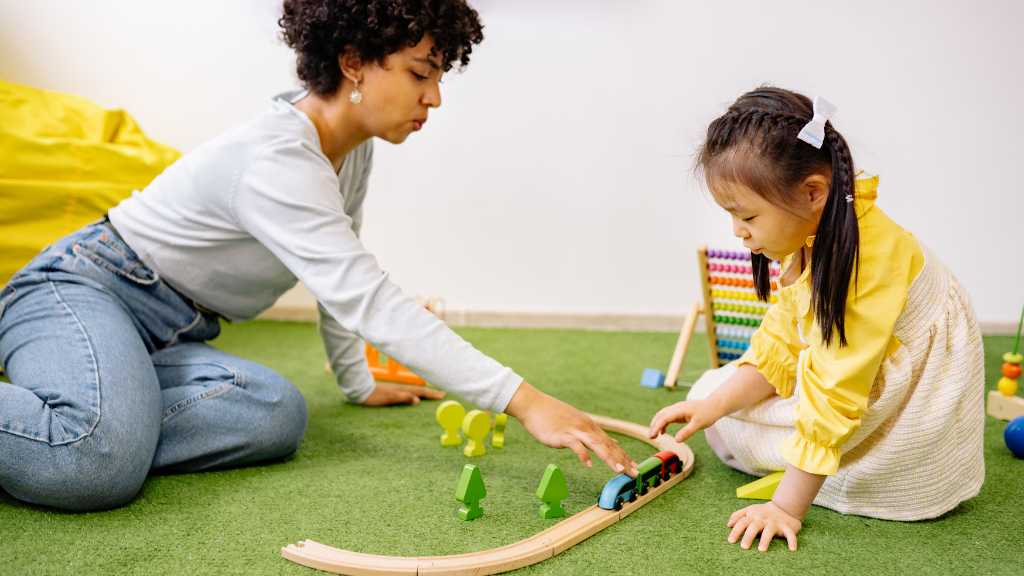 Therapist and toddler playing with toy train in play-based ABA therapy