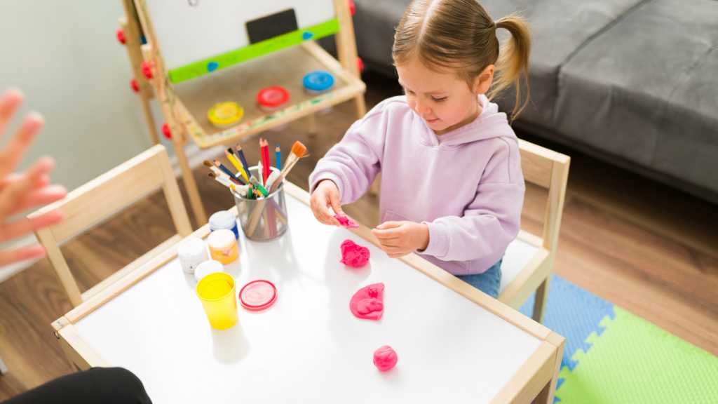 Toddler using playdough during play-based therapy for autism