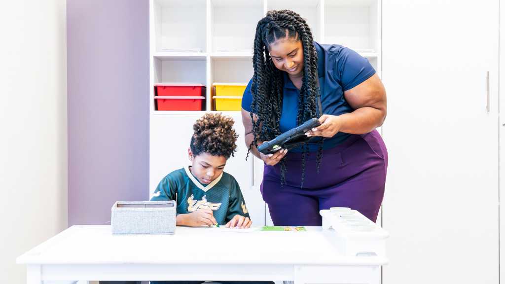 ABA therapist supports a child during a table activity