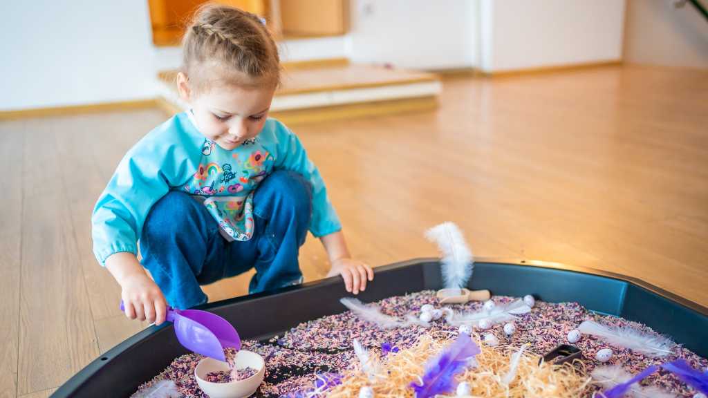 Toddler playing with sensory bin, sensory seeking vs sensory avoiding behavior