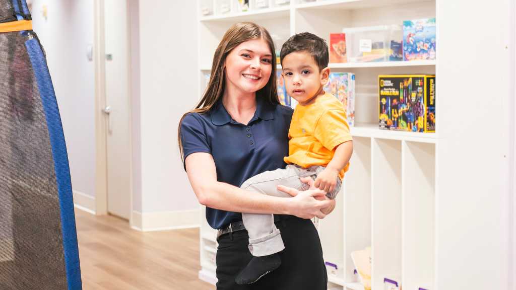 ABA therapist holding a young child in a therapy center